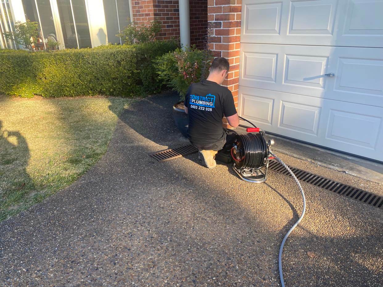 Plumber using water jetter to clear drain